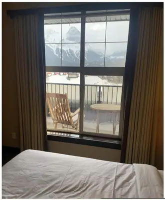 a bedroom with a bed and a view of a balcony at Canmore Mountain View in Canmore