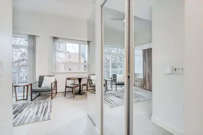 a living room with a table and chairs and mirrors at Modern Studio Condo in Central Prime Location in Vancouver