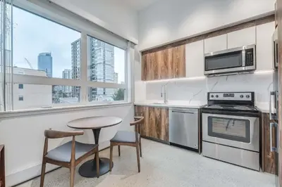 a kitchen with a table and a stove top oven at Modern Studio Condo in Central Prime Location in Vancouver