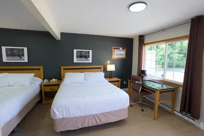 a bedroom with two beds and a desk and a window at Park Motel in Hope