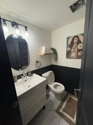 a bathroom with a sink and a toilet and a painting at Charming Mission Downtown Condo in Calgary