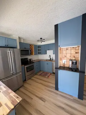 a kitchen with blue cabinets and stainless steel appliances at Charming Mission Downtown Condo in Calgary