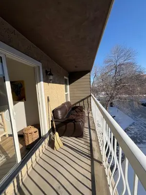 a porch with a leather chair and a broom at Charming Mission Downtown Condo in Calgary
