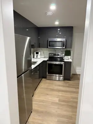 a kitchen with stainless steel appliances and wooden floors at Cozy 1 Bedroom suite close to west edmonton mall in Edmonton