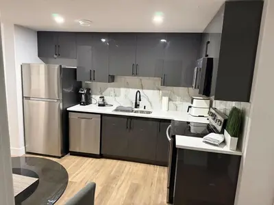 a kitchen with black cabinets and a stainless steel refrigerator at Cozy 1 Bedroom suite close to west edmonton mall in Edmonton