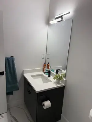 a bathroom with a sink and a large mirror at Cozy 1 Bedroom suite close to west edmonton mall in Edmonton