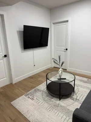 a living room with a table and a tv on a wall at Cozy 1 Bedroom suite close to west edmonton mall in Edmonton