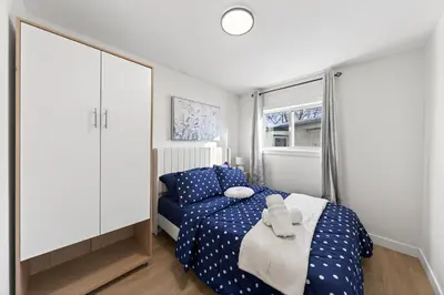 a bedroom with a blue bed and a white cabinet at Affordable & Cozy 3-bedroom, Minutes to City Core in Calgary