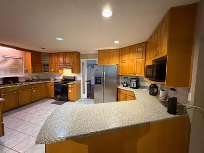 a kitchen with wooden cabinets and a stainless steel refrigerator at Surrey-Delta Urban Stay - Walk to Transit & Shopping in Surrey