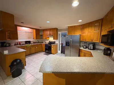 a kitchen with wooden cabinets and a stainless steel refrigerator at Nordel Way Guest House - Walk to Transit & Shopping - 20 Min to YVR in Surrey