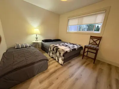 a bedroom with two beds and a window and a chair at Downtown Vancouver Cozy Room - Near SkyTrain, BC Place & Free Parking in Vancouver