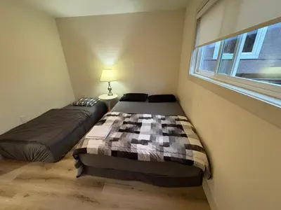 two beds in a small room with a window at Downtown Vancouver Cozy Room - Near SkyTrain, BC Place & Free Parking in Vancouver