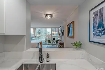 a white kitchen with a sink and a window at Beautiful Downtown Studio with Parking in Vancouver