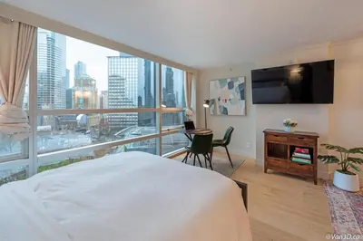 a bedroom with a bed and a large window at Beautiful Downtown Studio with Parking in Vancouver