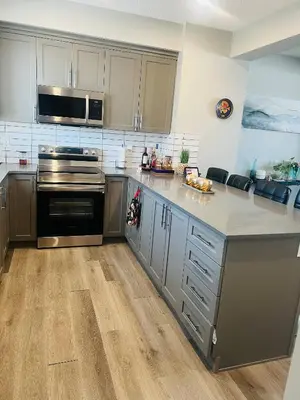 a kitchen with stainless steel appliances and wooden floors at Spacious Private Room with TV, WiFi and Fridge in Edmonton