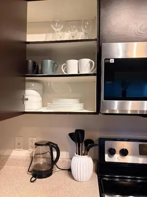 a kitchen with a microwave and some plates and glasses at Royal Bay Guest Suite in Victoria
