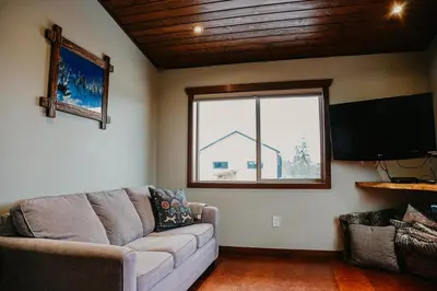 a living room with a couch and a large window at Big Bear Chalet and spa in Revelstoke