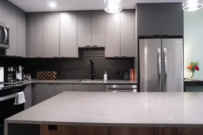 a kitchen with white cabinets and a stainless steel refrigerator at Tu Casa - 2 Bedroom Condo with Private Hot tub in Revelstoke
