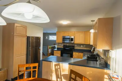 a kitchen with wooden cabinets and a black counter top at Bright 3BR Upper Suit, 23 min to Jasper NP in Hinton