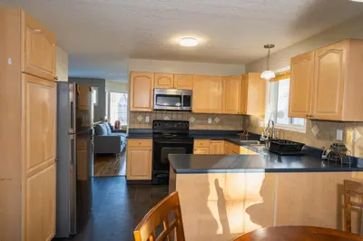 a kitchen with wooden cabinets and a stove top oven at Bright 3BR Upper Suit, 23 min to Jasper NP in Hinton