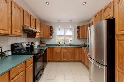 a kitchen with wooden cabinets and a stainless steel refrigerator at The Forest Pedal House in Squamish