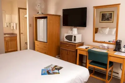 a hotel room with a bed and a desk with a computer at Chalet Inn in Kitimat