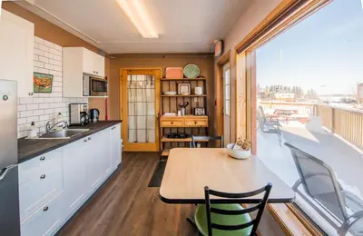 a kitchen with a table and a large window at Aurora Bayside Inn in Yellowknife