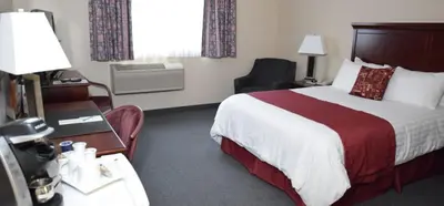 a hotel room with a large bed and a desk with a desk at Lakeland Inn Hotel in Cold Lake