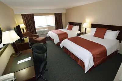 a hotel room with two beds and a desk at Lakeland Inn Hotel in Cold Lake