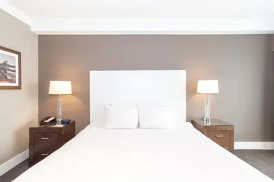 a bedroom with a large white bed with two lamps at Sandman Hotel Abbotsford Airport in Abbotsford