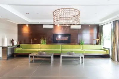 a living room with a green couch and a chandelier at Sandman Hotel Abbotsford Airport in Abbotsford