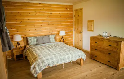 a bedroom with a bed and a wooden wall at Southern Lakes Resort in Tagish