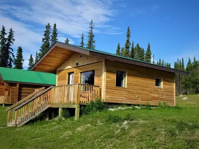 a log cabin with a green roof at Southern Lakes Resort in Tagish