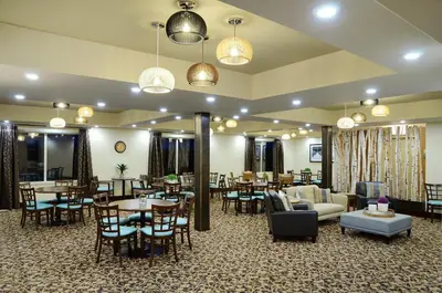 a hotel room with tables and chairs and a lobby at Pomeroy Inn and Suites Vermilion in Vermilion