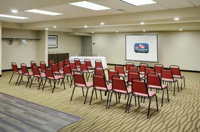 a conference room with red chairs in front of a screen at Pomeroy Inn and Suites Vermilion in Vermilion