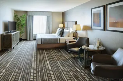 a hotel room with a bed and chairs and a television at Pomeroy Inn and Suites Vermilion in Vermilion