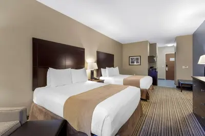 a hotel room with two beds and a couch at Best Western PLUS Fort Saskatchewan Inn & Suites in Fort Saskatchewan