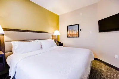 a hotel room with a white bed and a flat screen tv at Candlewood Suites West Edmonton - Mall Area by IHG in Edmonton