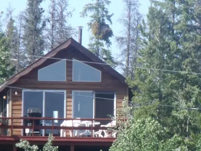 a cabin in the woods with a wrap around deck at Nimpo Lake Resort in Nimpo Lake