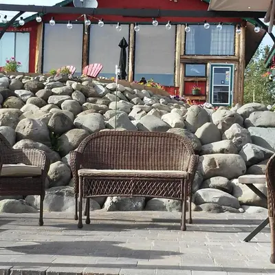 a wicker bench sitting in front of a rock wall at Nimpo Lake Resort in Nimpo Lake