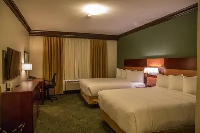 a hotel room with two beds and a desk at Chateau Nova Peace River in Peace River