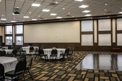 a banquet hall with tables and chairs and a projection screen at Chateau Nova Peace River in Peace River