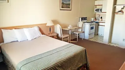 a hotel room with a bed and a kitchen at Badlands Motel in Drumheller
