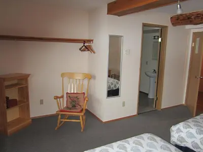 a bedroom with a chair and a bed and a bathroom at Smithers Driftwood Lodge in Smithers