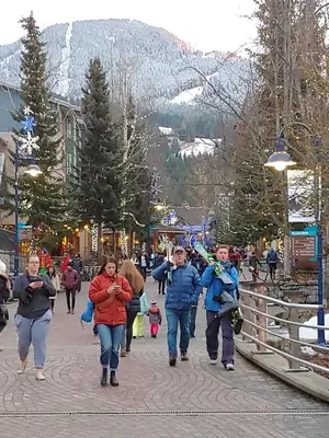 a group of people walking down a street at Tyndalstone Lodge 3 Bedroom in the Heart of Village North Whistler in Whistler