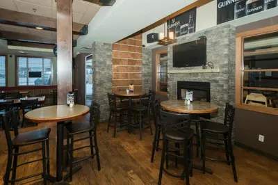 a restaurant with wooden tables and chairs and a fireplace at Lakeview Inns & Suites - Fort Saskatchewan in Fort Saskatchewan