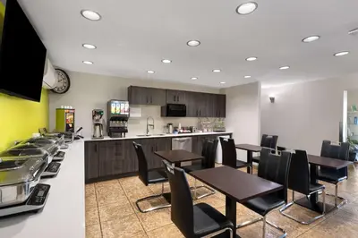 a restaurant with tables and chairs and a kitchen at Super 8 by Wyndham Fort McMurray in Fort McMurray