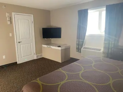 a room with a bed and a television and a window at Super 8 by Wyndham Fort McMurray in Fort McMurray