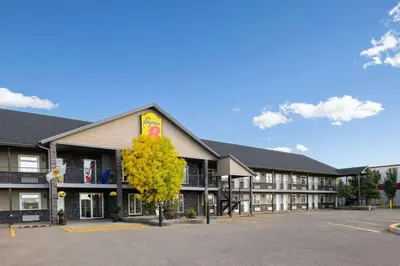 a hotel building with a yellow tree in the parking lot at Super 8 by Wyndham Fort McMurray in Fort McMurray