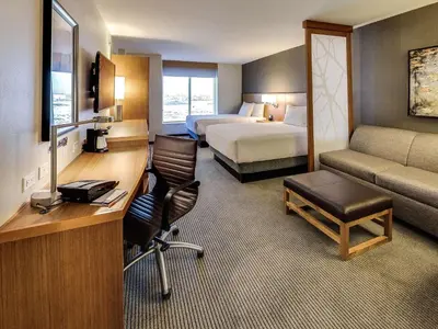 a hotel room with a desk and a bedroom at Hyatt Place Edmonton West in Edmonton